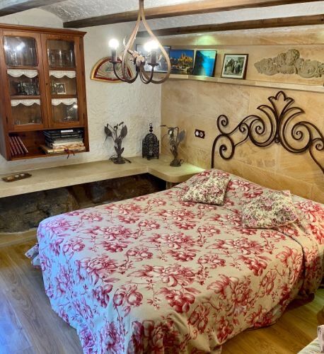 A ground-floor room with an ornate wrought-iron headboard, a floral spread and a glazed display cabinet.